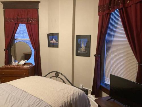 a bedroom with red curtains and a bed and a mirror at Queen Bed with Shared Bathroom in Lakeview - 2b in Chicago