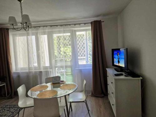 a living room with a table with chairs and a television at Great Apart Imielin in Warsaw