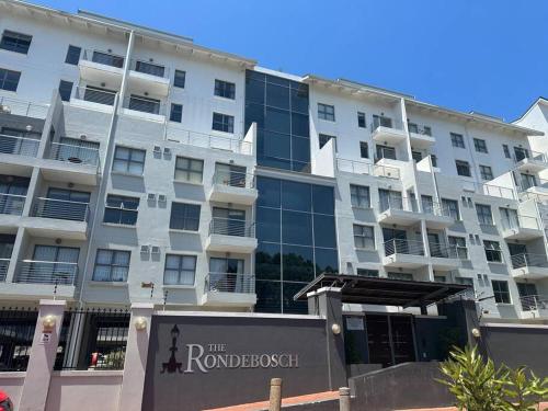 un gran edificio blanco con un cartel delante en Cozy Rondebosch Apartment, en Ciudad del Cabo