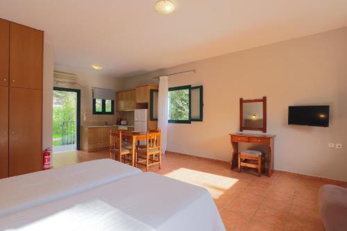 a bedroom with a bed and a table and a kitchen at Vivi's Apartments in Ayia Evfimia