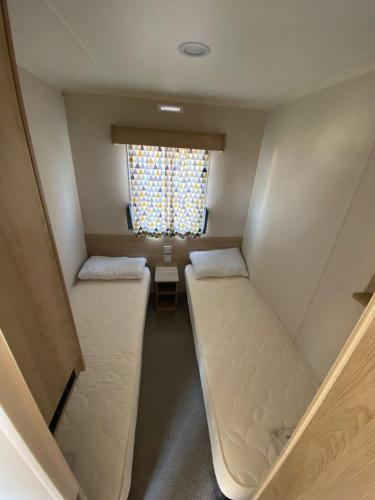 Cette petite chambre comprend 2 lits et une fenêtre. dans l'établissement Hillside Sleeps 6, à Allhallows