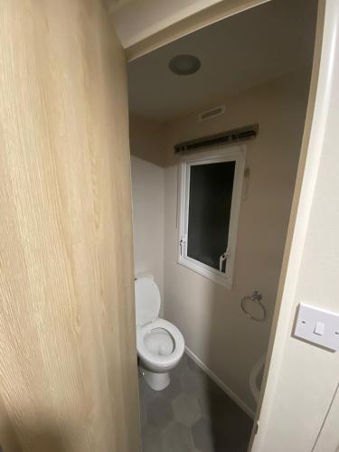 a bathroom with a toilet and a window at Hillside Sleeps 6 in Allhallows