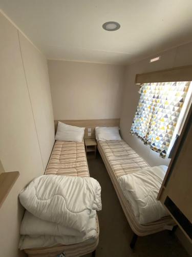 Hillside Sleeps 6 في Allhallows: سريرين في غرفة صغيرة مع نافذة