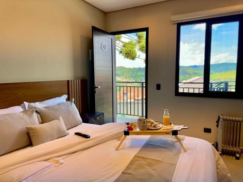 a bedroom with a bed with a table and windows at Villa Cristalle - Campos do Jordão in Campos do Jordão