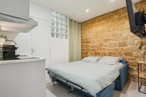 - un lit dans une cuisine avec un mur en briques dans l'établissement Tiny Suite 12 D Paris’s heart!, à Paris