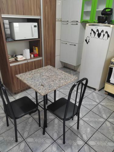 cocina con mesa, 2 sillas y nevera en Gray House 3 - JD. Leonor en Londrina