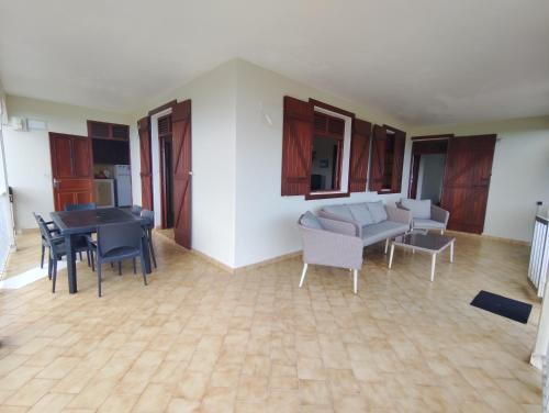 ein Wohnzimmer mit einem Sofa, einem Tisch und Stühlen in der Unterkunft Location Hibiscus in Pointe-Noire