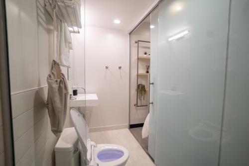 a white bathroom with a toilet and a shower at SOVA Micro-Room & Social Hotel in Dallas