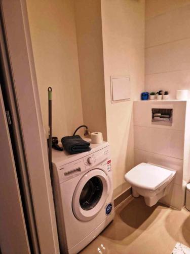 a bathroom with a washing machine and a toilet at Great Apart Kabaty in Warsaw