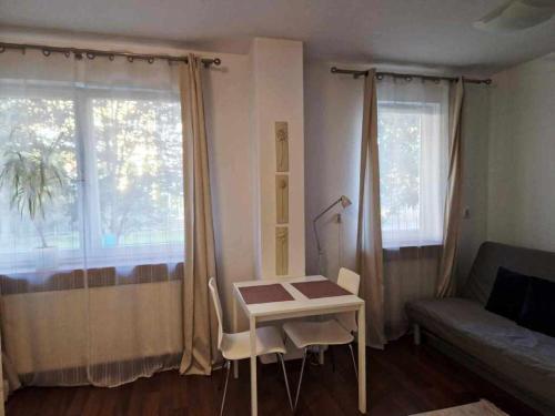 uma sala de estar com uma mesa, um sofá e uma janela em Great Apart Kabaty em Varsóvia