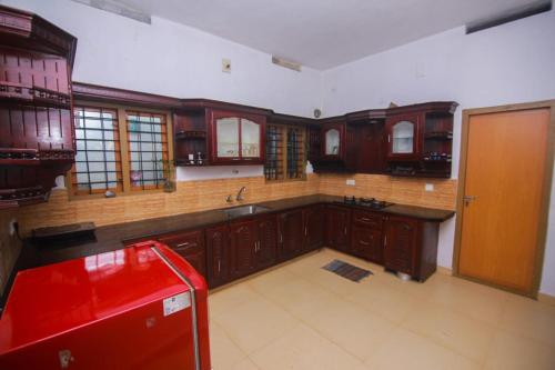 een grote keuken met houten kasten en een rood apparaat bij Maverick Holidays Inn Family Villa in Vagamon