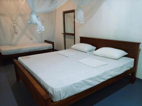 a bedroom with two beds with white sheets and a mirror at AB Nest Hiriketiya in Dickwella