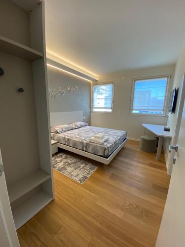 a bedroom with a bed and a desk and two windows at HZ+ Costantini in Pordenone