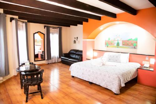 a bedroom with a bed and a table and a couch at Hotel Catedral in San Cristóbal de Las Casas
