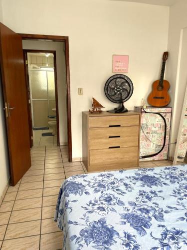 a bedroom with a bed and a dresser with a fan at Quarto privativo in Balneário Camboriú