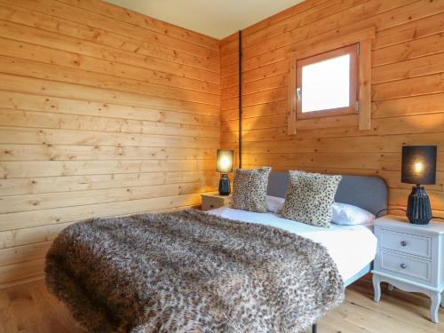 a bedroom with wooden walls and a bed and two lamps at Otter's View in Oakham