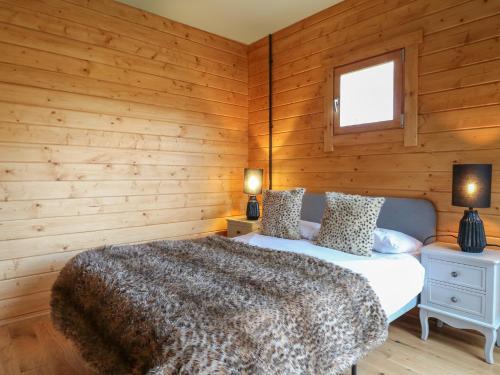 a bedroom with wooden walls and a bed and two lamps at Squirrel's Nest in Oakham