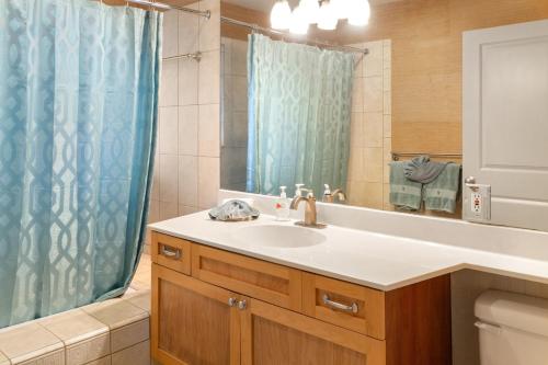 baño con lavabo y cortina de ducha azul en Lotus Suite in a Boutique Resort, 1Bedroom Sleeps 4 en Kihei