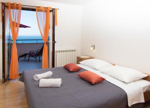 sypialnia z łóżkiem z 2 poduszkami i oknem w obiekcie Apartments Grzin w mieście Mošćenička Draga