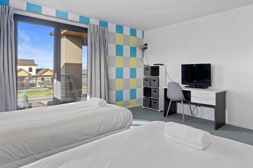 a bedroom with two beds and a desk with a television at Waterfront Lake Hood Luxury in Wakanui