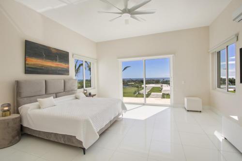 a white bedroom with a bed and a large window at Villa Okyanus with Fantastic Ocean View Chef Butler Maid Golf Cart in Punta Cana