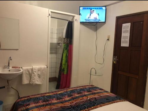 een badkamer met een bed en een tv aan de muur bij HotelMidnight78 in Paramaribo