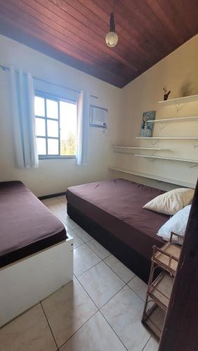 1 dormitorio con 2 camas y ventana en Casa Praia das Dunas Residence Club, en Cabo Frío