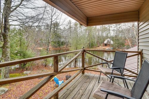 two chairs on a deck with a view of a pond at Cozy Thompson Lake Cabin with Boat Dock and Launch in Dunkertown