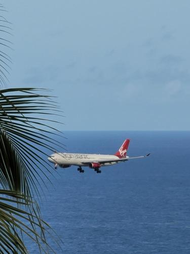 an airplane is flying over the ocean at Airport Heights Apartment in Mesopotamia