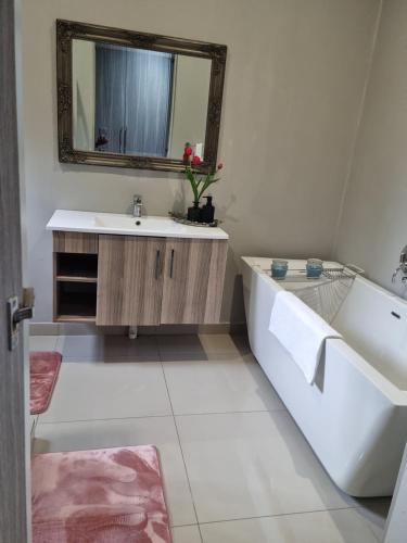 y baño con bañera, lavabo y espejo. en The Packwood Cottage, en Johannesburgo