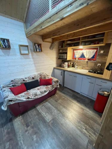 a living room with a couch and a kitchen at La p'tite maison bois du hérisson in Ménétrux-en-Joux