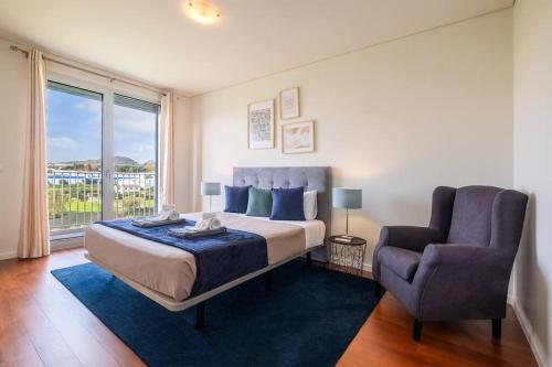 a bedroom with a bed and a chair and a window at Quiet & Comfy Azorean Sapphire in Fajã de Baixo