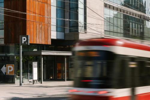 a bus driving down a city street with tall buildings at Sonder at The Liberty in Toronto