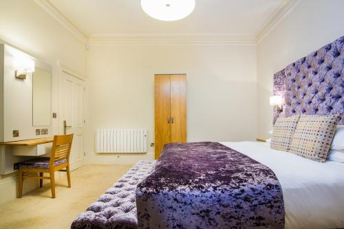 a bedroom with a large bed and a desk at White Hart Hotel & Apartments in Harrogate