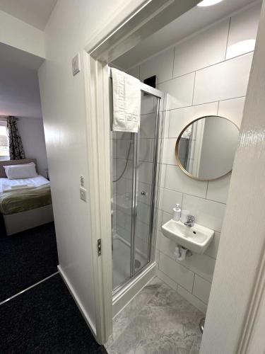 a bathroom with a shower and a sink and a mirror at Newmarket Road Studios and Suites By Tas Accommodations in Cambridge