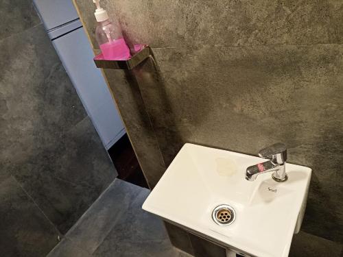 a bathroom with a sink and a bottle of pink soap at Saffron Dormitory Goregaon East in Mumbai