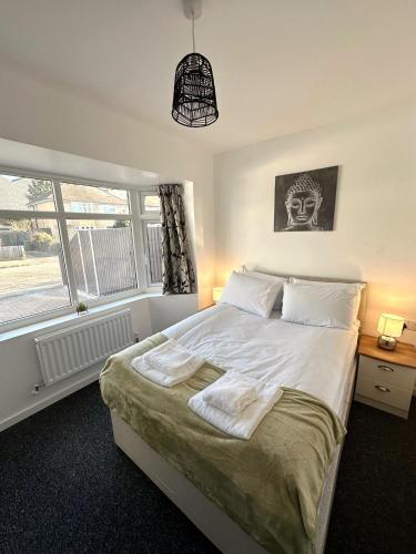 Schlafzimmer mit einem Bett mit weißer Bettwäsche und einem Fenster in der Unterkunft Newmarket Road Studios and Suites By Tas Accommodations in Cambridge