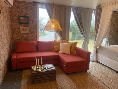 ein Wohnzimmer mit einem roten Sofa vor einem Fenster in der Unterkunft Pia’s Country House in Båstad