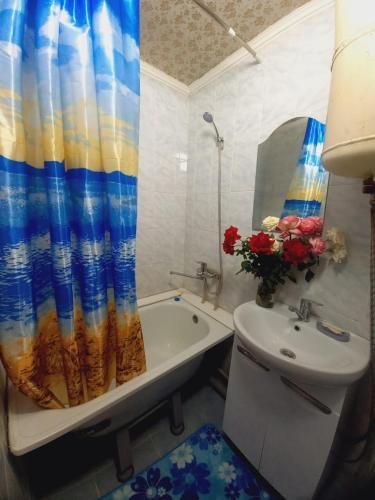 uma casa de banho com uma banheira, um lavatório e uma cortina de chuveiro em Medina em Karakol