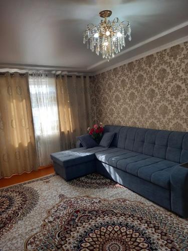 a blue couch in a living room with a chandelier at Medina in Karakol