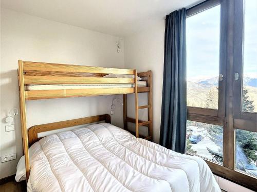 una camera da letto con un letto a castello e una grande finestra di Duplex spacieux au pied des pistes avec accès piscine - FR-1-267-255 a Villarembert