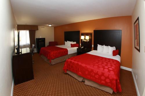 a hotel room with two beds with red sheets at Ramada by Wyndham Fresno North in Fresno