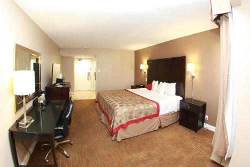 a hotel room with a bed and a desk at Ramada by Wyndham Fresno North in Fresno