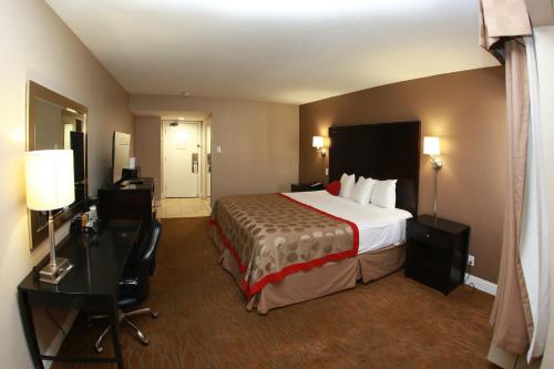 a hotel room with a large bed and a desk at Ramada by Wyndham Fresno North in Fresno
