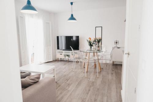 a white living room with a table and a tv at Marimel Nerja Alojamientos in Nerja