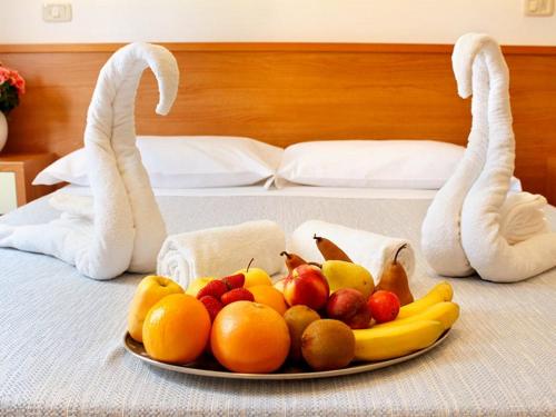 a plate of fruit on a bed with towels at PFA Hotel La Darsena - Follonica in Puntone di Scarlino
