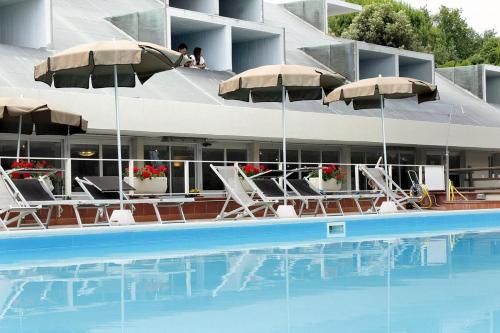 a swimming pool with chairs and umbrellas next to a building at PFA Hotel La Darsena - Follonica in Puntone di Scarlino