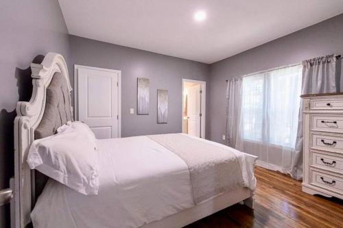a bedroom with a white bed and a dresser at The Bungalow in the City - Minutes to Downtown! in Birmingham