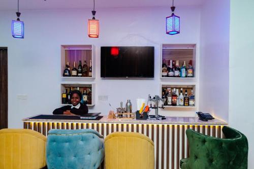 a bar with two chairs and a woman behind a counter at LA FIFTHIN VILLA in Lekki