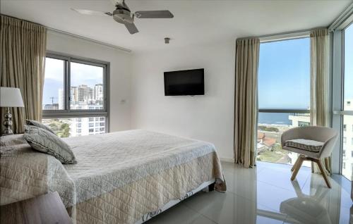 a bedroom with a bed and a tv and windows at Wind Tower, Punta del Este in Punta del Este